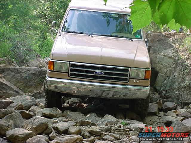 tan Ford Bronco navigating a rocky trail, front view