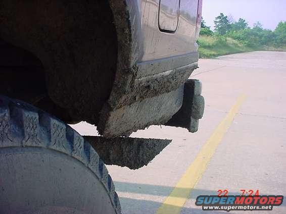 Mud covers the fender, tire, and lower body of a vehicle