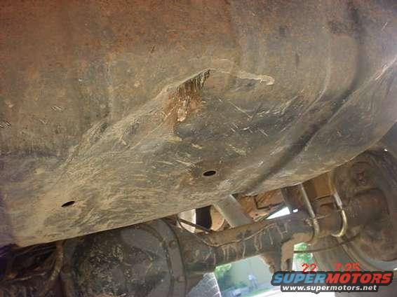 Undercarriage of a 1989 Ford Bronco showing rust and damage to the fuel tank and suspension