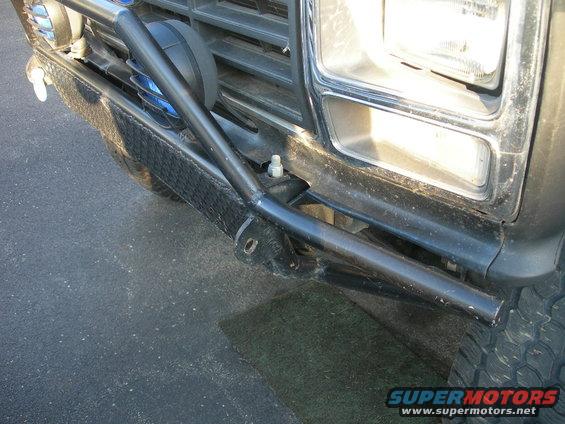 Front bumper and headlight of a 1980s era truck with a brush guard