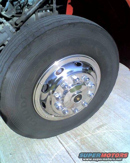 Close-up of a flat tire with chrome hubcaps on a large vehicle, showing the Goodyear logo