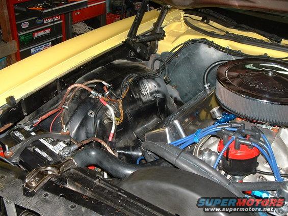 Yellow vehicle engine bay with battery, wiring, and air filter visible