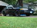 2003 Ford Crown Victoria - A black 2003 Ford Crown Victoria sedan is parked in front of a house and garage.