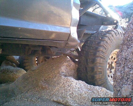 Off-road vehicle with large tires navigating rocky terrain. Roll cage visible