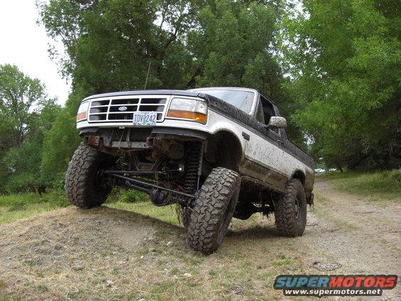 1993 Ford Bronco with lifted suspension and large tires on a dirt hill