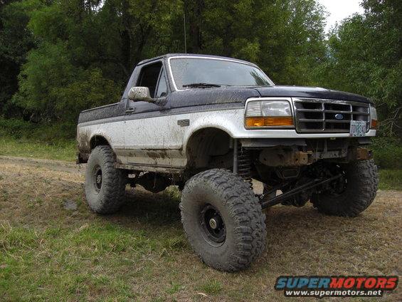 Lifted 1993 Ford Bronco with large tires parked on a dirt road