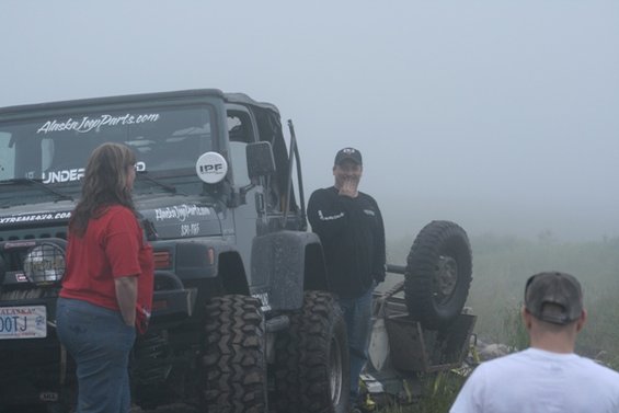 Jeep Wrangler with "Alaska Jeep Parts.com" sticker, people standing nearby, foggy conditions