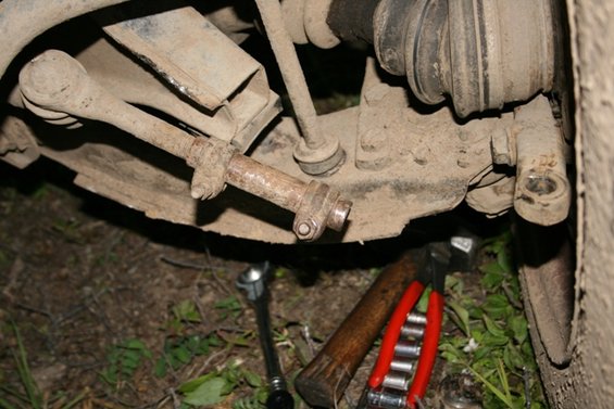 Close-up of rusty vehicle suspension parts with tools on the ground