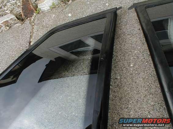 Two black car door frames with glass, one angled left, the other right, on a concrete surface