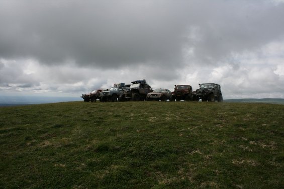 Several vehicles parked in a grassy field under a cloudy sky