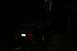 1990 Chevrolet Suburban - A station wagon is parked on a dirt path in the woods at night, with another vehicle visible in the distance.