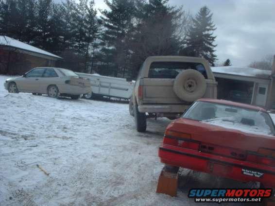 Tan 1980s Ford Bronco rear view with spare tire, parked in snow