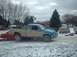 1986 Ford Bronco - Several vehicles are parked in a snowy lot, with one pickup truck appearing to be on top of a red car.