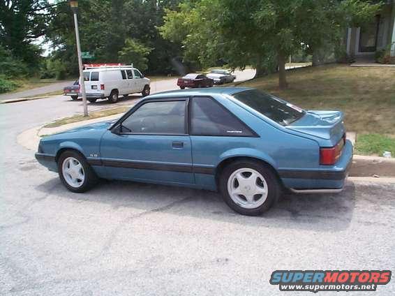 Blue 1987 Ford Mustang coupe with a spoiler and five-spoke wheels