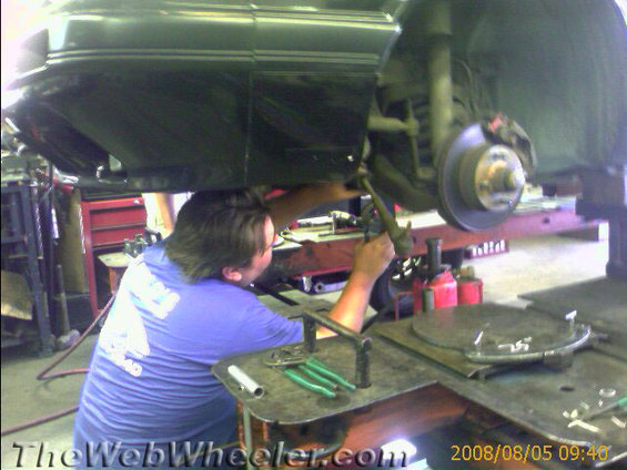 Suspension repair on a dark-colored vehicle, viewed from below
