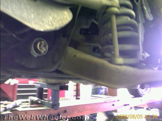 close-up of car's front suspension system with shock absorber and control arm visible