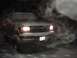 1996 Ford Bronco - A Ford truck is covered in snow, with its headlights on, emitting exhaust in the cold night air.