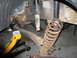 1991 Ford Bronco - Vehicle suspension components are visible, including a shock absorber and a rusty coil spring, with a jack supporting the frame.