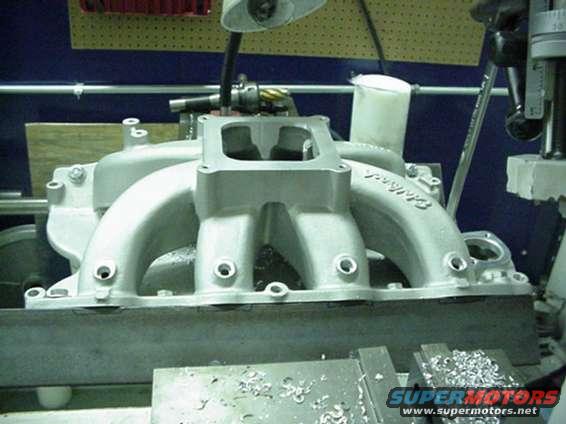 Aluminum intake manifold with Edelbrock branding on a workbench, metal shavings visible