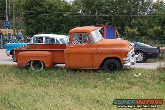 Orange 1955 GMC pickup truck, side view, with white-wall tires and chrome bumper