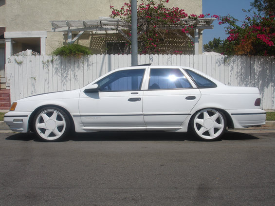 White 1990 Ford Taurus sedan, side view, with custom wheels