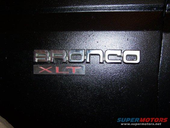 Bronco XLT emblem on black textured surface