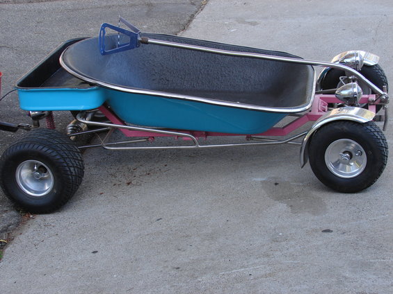 Go-kart made from a bathtub on a pink frame with small wheels and chrome fenders