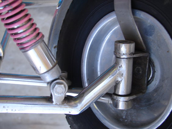 Close-up of a motorcycle's chrome swingarm, pink-coated shock absorber, and wheel