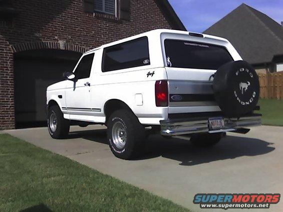 White 1996 Ford Bronco parked in a driveway, rear view with spare tire cover