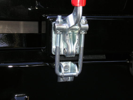 Black surface with a silver metal latch mechanism with a red handle