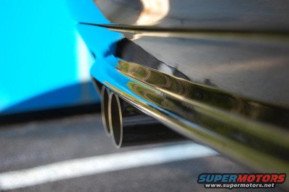 Chrome exhaust pipes on a car with a blue body panel