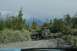1990 Chevrolet Suburban - A Jeep Cherokee tows a trailer down a dirt road, with a dog walking behind it and mountains in the distance.