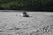 1990 Chevrolet Suburban - A silver SUV with a trailer is being towed through a rocky riverbed.