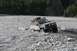 1990 Chevrolet Suburban - This modified Jeep Cherokee XJ navigates a shallow, rocky river, kicking up water.