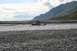 1990 Chevrolet Suburban - An off-road vehicle navigates a shallow, rocky river, with a mountainous landscape visible behind it.