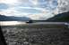 1990 Chevrolet Suburban - An SUV is stuck in a riverbed under a cloudy sky with mountains in the distance.
