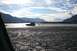 1990 Chevrolet Suburban - SUV navigates a rocky riverbed under a partly cloudy sky with mountain ranges in the distance.