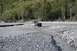 1990 Chevrolet Suburban - Off-road vehicle navigates a shallow, rocky river with trees lining the bank.