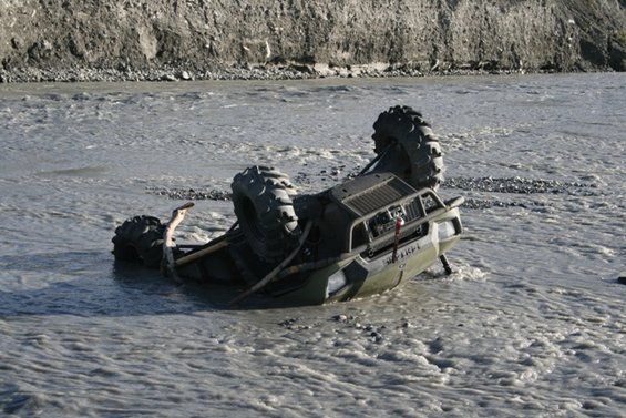 Overturned ATV in muddy water, text visible on side