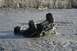 1990 Chevrolet Suburban - An ATV is overturned in a shallow, muddy river, with its wheels in the air.