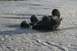 1990 Chevrolet Suburban - An ATV is overturned in a shallow, muddy river, with a tow rope attached.