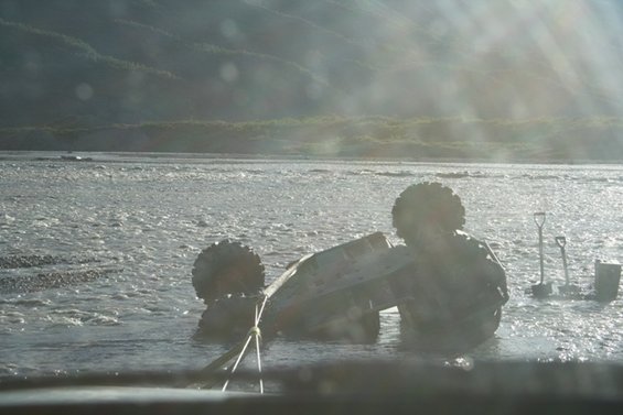 Vehicle overturned in shallow river with two shovels nearby