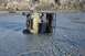 1990 Chevrolet Suburban - An ATV is submerged and overturned in a river, with a tow cable attached.