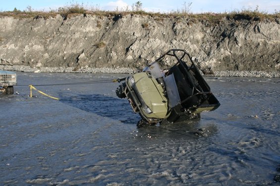 Off-road vehicle stuck in river, being pulled by a truck