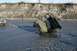 1990 Chevrolet Suburban - A truck is pulling an ATV out of a muddy riverbed, with a steep bank in the background.