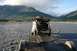 1990 Chevrolet Suburban - A person loads gear into an SUV parked in a shallow river, with a trailer attached and mountains in the background.