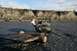 1990 Chevrolet Suburban - Two people in a green utility vehicle tow a trailer through a rocky riverbed.