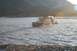 1990 Chevrolet Suburban - A Jeep Cherokee XJ navigates a river while towing a trailer, with a mountainous landscape in the background.