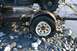 1990 Chevrolet Suburban - A trailer with a flat tire and a portion of a vehicle is situated on a rocky shore next to water.