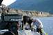 1990 Chevrolet Suburban - Two men work near a Polaris Ranger ATV on a rocky shore with a mountain in the background.